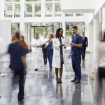 Female doctor and male nurse have a discussion in the middle of a busy hallway