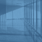 Woman walking through green atrium underneath a skyscraper.