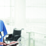 Close up of a nurse with a stethoscope looking down and smiling.