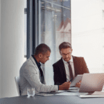 Two men in suits working in a conference room.