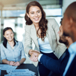 Enthusiastic businesswoman shaking hands with a coworker in a conference room. 